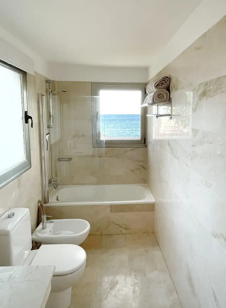 Marble bathroom with bathtub and a window to the sea